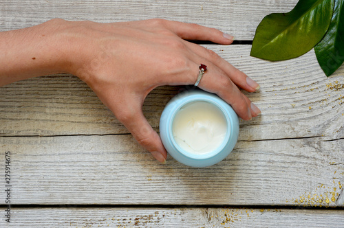 Face cream on vintage wooden white background with female hands. Anti-aging cream in the hands. Female hands holding a jar of cream. Body cream