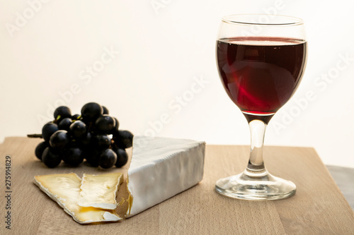 glass of red wine and grapes on white background