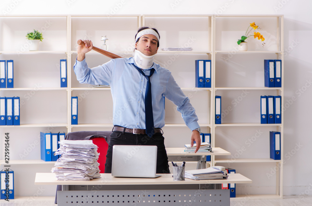 Young injured male employee working in the office 