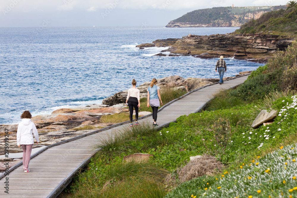 Obraz premium People walking along the boardwalk on the New South Wales coastline near Freshwater Bay, Sydney, Australia