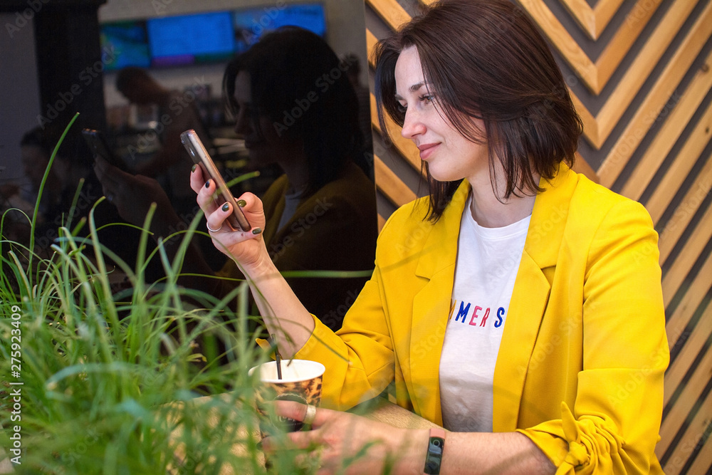 A charming woman reads good news on a mobile phone while relaxing in a cafe, a happy brunette looks at her photo on a mobile phone while relaxing in a cafe in her free time. Instant messenger A charming woman reads good news on a mobile phone while relaxing in a cafe, a happy brunette looks at her photo on a mobile phone while relaxing in a cafe in her free time. Instant messenger