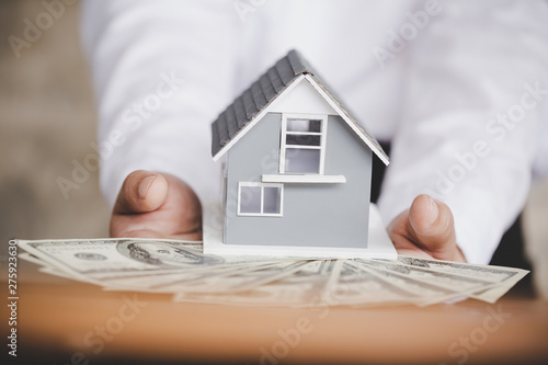 mortgage, investment, real estate and property concept - close up of home model on dollar money