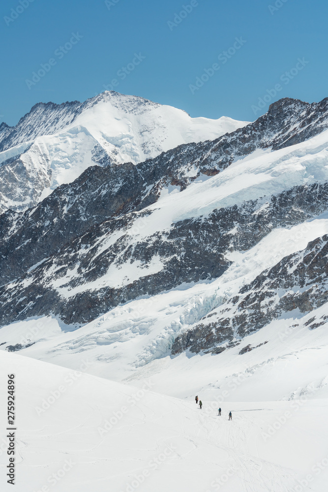 Swiss Alps mountain range landscape full of snow in winter, with group of traveler trekking to summit Swiss Alps mountain range landscape full of snow in winter, with group of traveler trekking to summit