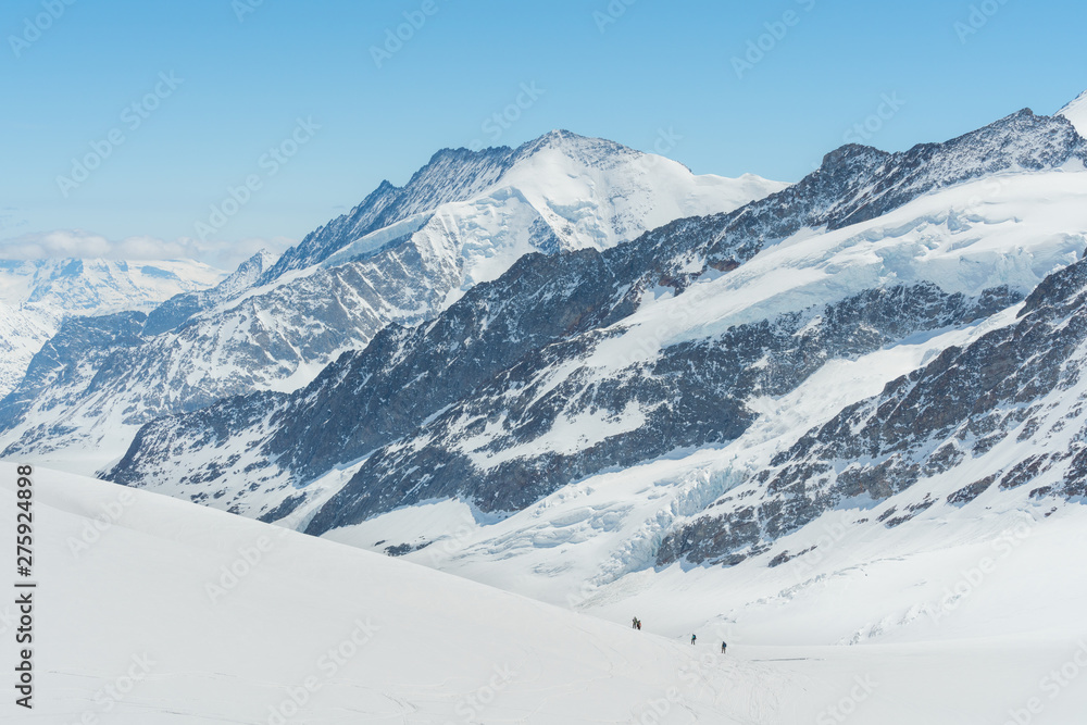 Swiss Alps mountain range landscape full of snow in winter, with group of traveler trekking to summit Swiss Alps mountain range landscape full of snow in winter, with group of traveler trekking to summit