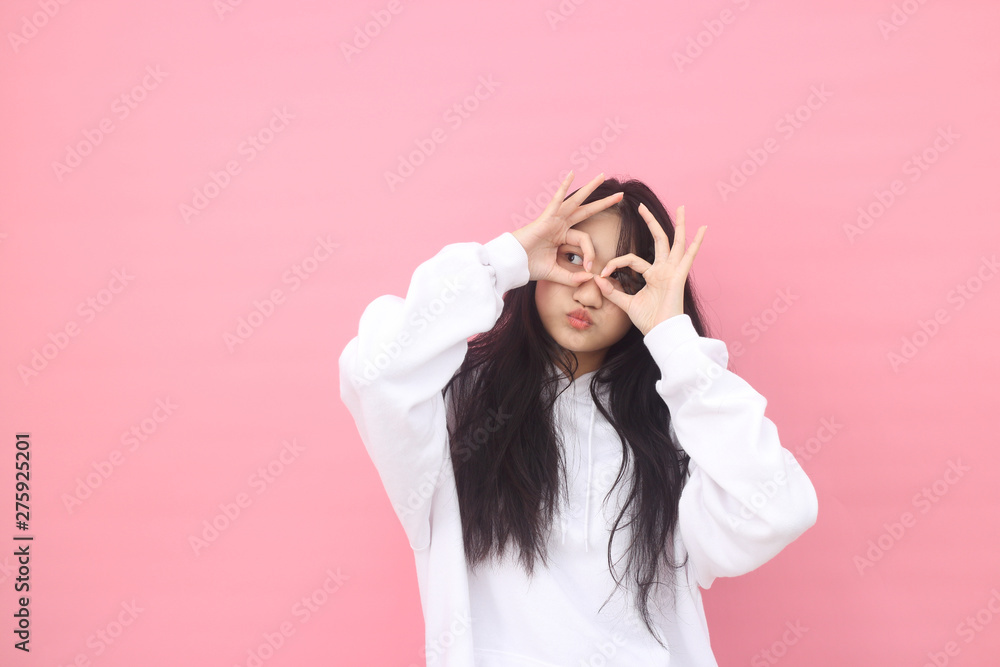 Isolated shot of pretty Beautiful Asian models over pink background for advertising concept , wears casual outfit, being entertained by friend during party Isolated shot of pretty Beautiful Asian models over pink background for advertising concept , wears casual outfit, being entertained by friend during party