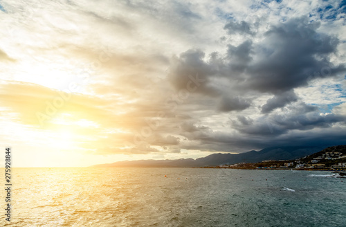 sun's rays clouds over the mountains on coast of Crete, Greece. Early morning, coastline with hotels