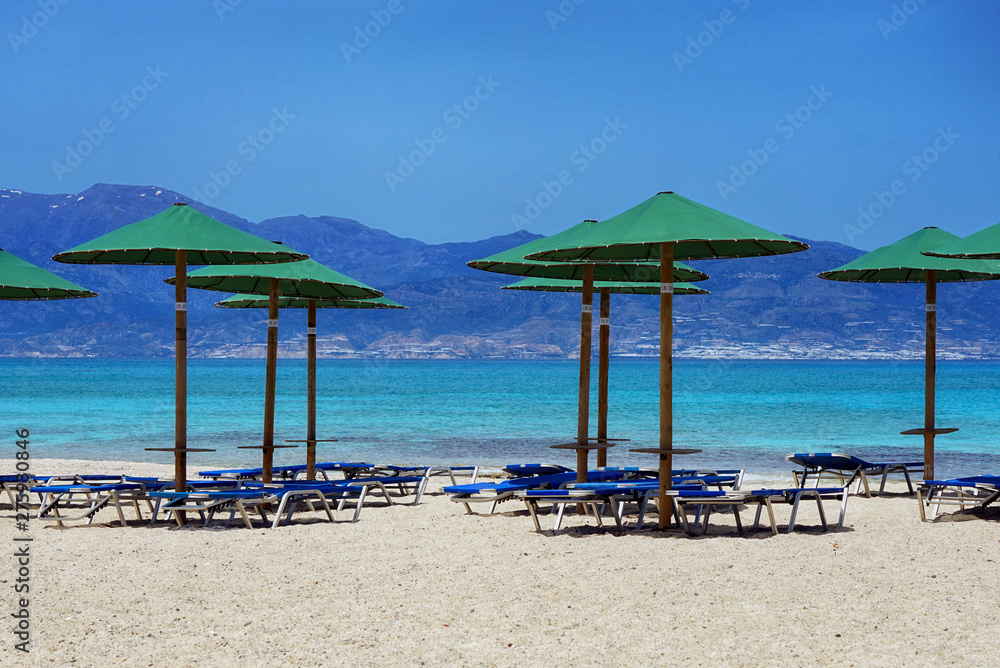 Liegen und Sonnenschirme am Strand mit türkisblauem Wasser
