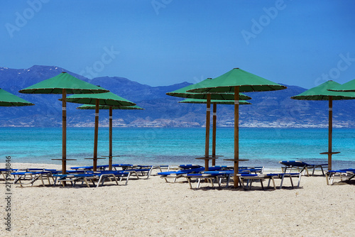 Liegen und Sonnenschirme am Strand mit türkisblauem Wasser