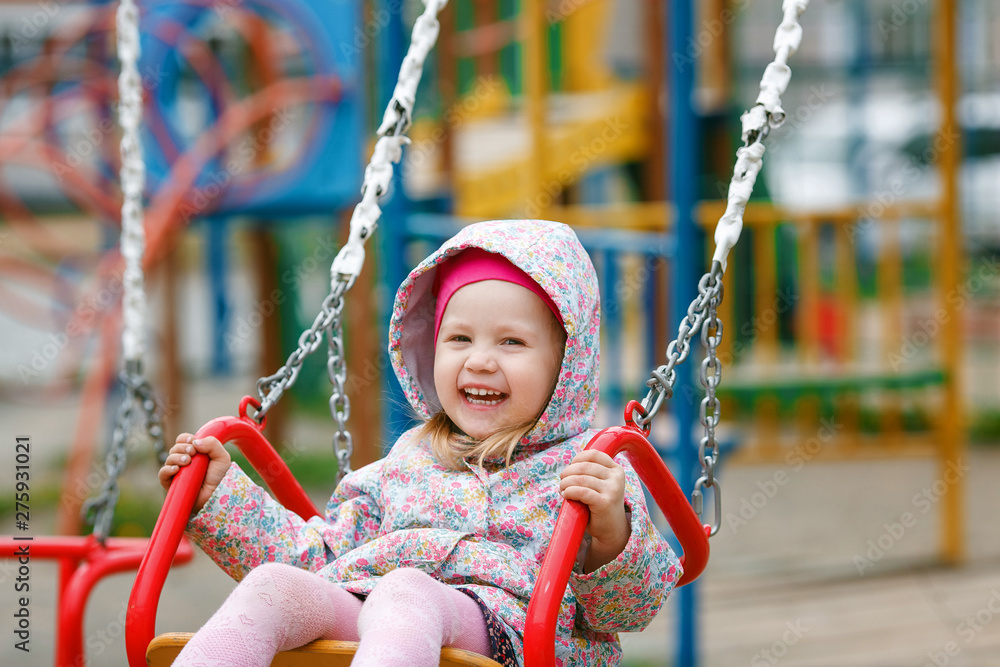 Happy little girl having fun with swing in the park. Children playground. Happy little girl having fun with swing in the park. Children playground.
