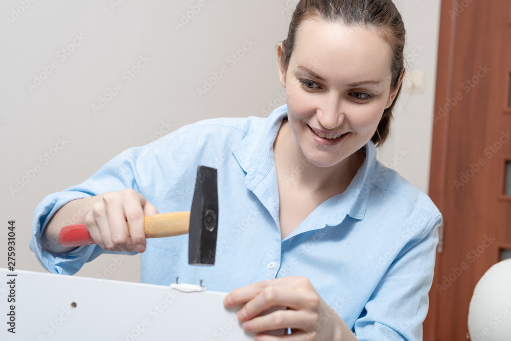 Close-up of a young woman with a hammer, furniture Assembly Close-up of a young woman with a hammer, furniture Assembly