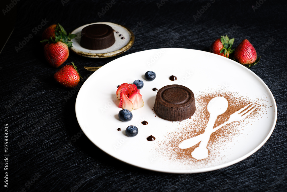 Fototapeta premium Molten chocolate lava cake with berries on white plate.