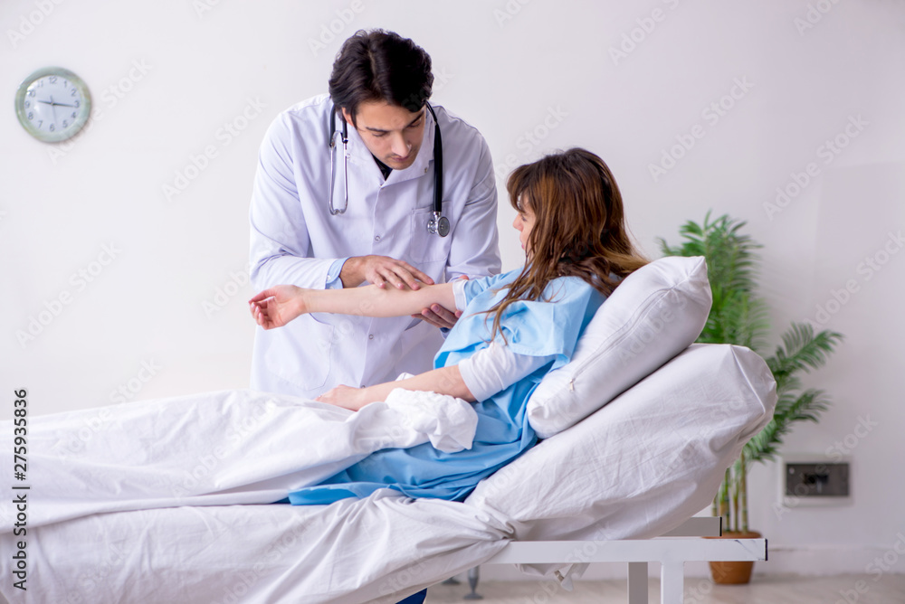 Fototapeta premium Male doctor visiting female patient in ward 