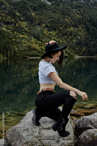 Girl sitting on rocks near lake. Tatra mountains landscape in Poland, Zakopane. Mountain landscape in Eastern Europe.