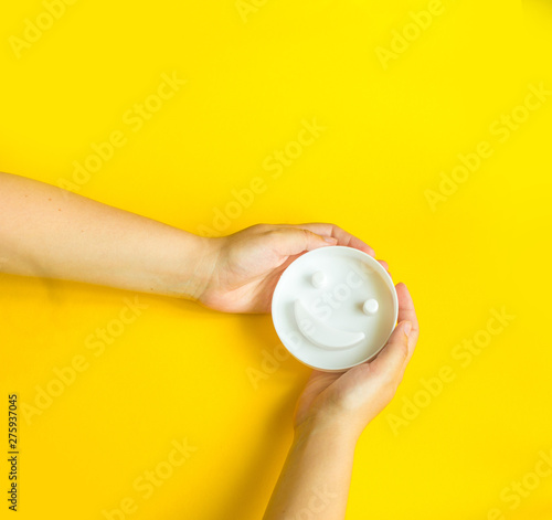 Fototapeta Naklejka Na Ścianę i Meble -  Smiley in woman's hands on yellow background with copy space. Happy work day concept