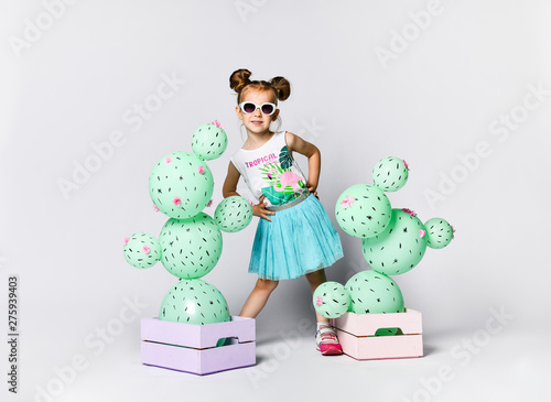 Young blond girl 4 years with cactus ball in a pastel pink wooden box. The flowers are made of balloons with pink flowers and painted spines photo