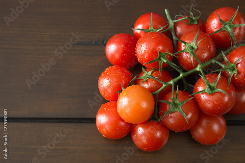 Fresh and juicy cherry tomatoes with branch on wooden background