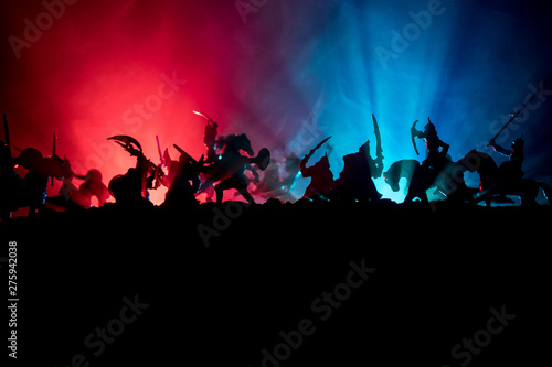 Medieval battle scene with cavalry and infantry. Silhouettes of figures as separate objects, fight between warriors on dark toned foggy background with medieval castle.