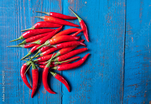 Red ripe small chili peppers pattern over old wooden blue background, flat lay.