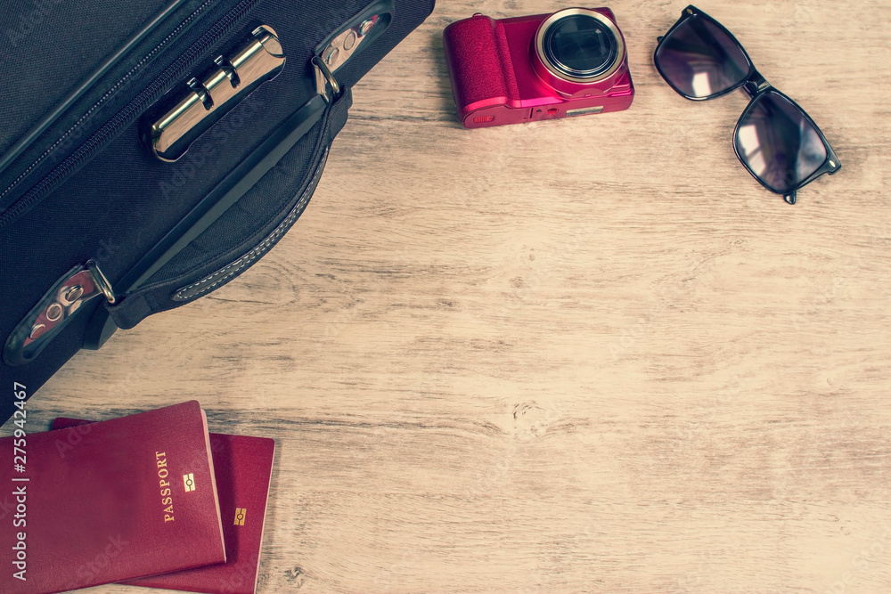 Naklejka premium accessories and items for travel on wooden board. Suitcase, passports, sunglasses, camera. Flat lay, top view. Vacation planning concept.