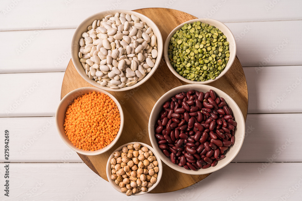 Top view of assortment of peas, lentils, beans and legumes over white wooden background.