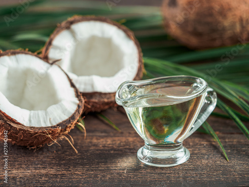 Foto Liquid coconut MCT oil and halved coco-nut on wooden table