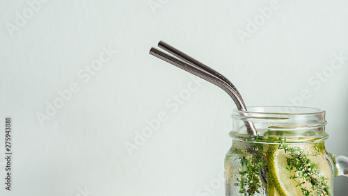 Cold drink in mason jar with metal straw on white background. Lemonade or detox water with lime and thyme in glass jar with copy space for text or design. Recyclable straws, zero waste concept. Banner photo