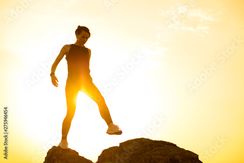 Slika na platnu Young Beautiful Woman Walking on the Rocks in the Mountains at Summer Sunset