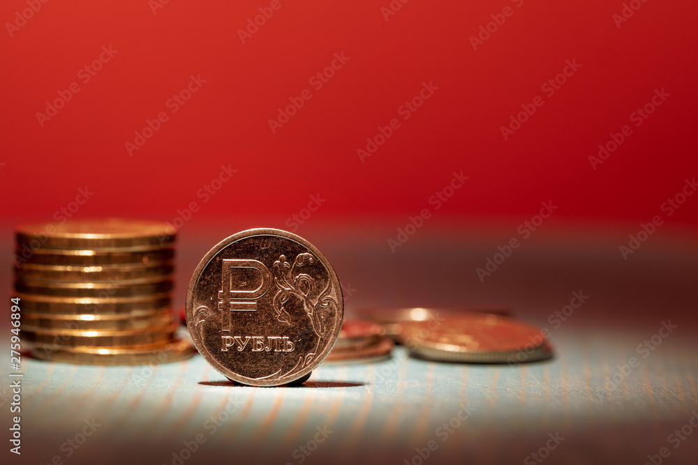 on a red gloomy background metal coin Russian ruble in stacks and the front side, snatched a beam of light old