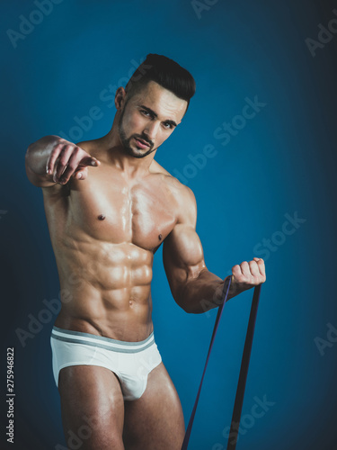 Attractive handsome guy encourages you to train with him. Young naked male model with perfect well trained body motivates you to do sport everyday. Advertising concept of sport and equipment. photo