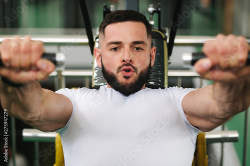 A young athlete trains in the gym. Bodybuilder trains the muscules of the chest photo