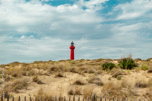 lighthouse at the sandy beach dunes with cloudy sky