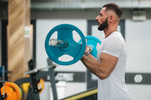 A young athlete trains in the gym. Trians biceps muscules photo