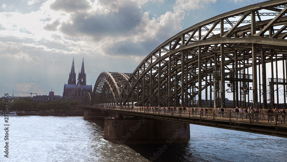 Cologne hohenzollern bridge at midday with many pedestrians, tourists walking on the bridge 