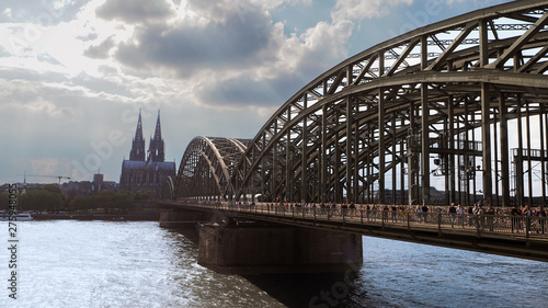 Cologne hohenzollern bridge at midday with many pedestrians, tourists walking on the bridge 