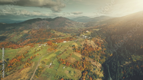 Autumn Multi Colored Mountain Landscape Aerial View. High Hill Tree Forest Scenery  Cloudy Sky. Green Slope Surface Countryside Village. Clean Ecology  Travel Concept. Drone Flight