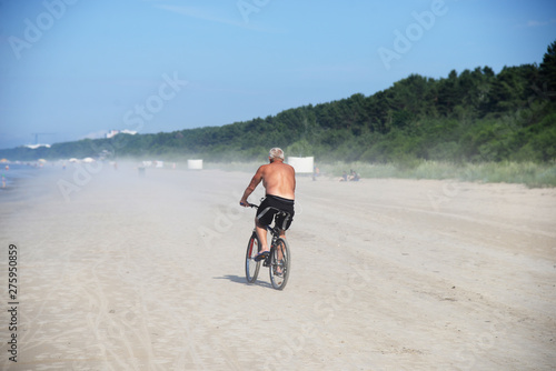 senior man riding bike on the beach