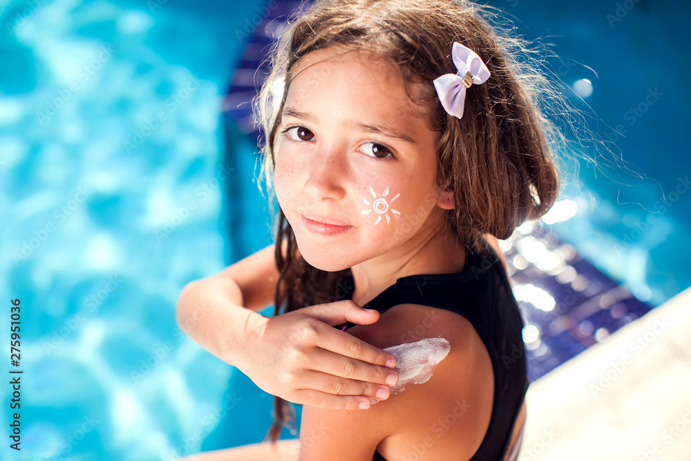 Kid girl applies sun protection cream on the skin. Children, summer