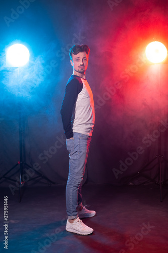 Slim young bearded hipster man in casual clothes posing on a red blue background. Concept of style and confidence.