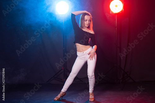 Dance, grace and elegance concept - young woman dancing bachata lady style in the dark, lights and smoke