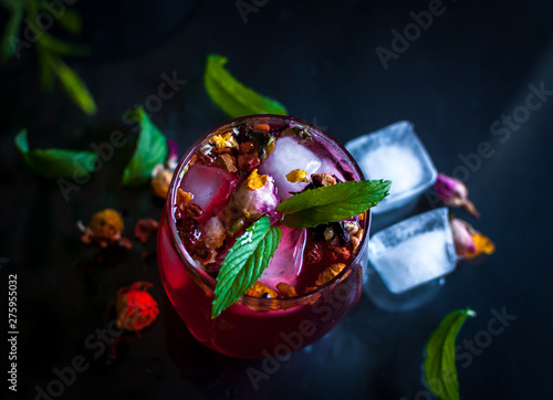 Close-up of homemade flower ice tea in a glass with fresh mint, on dark background