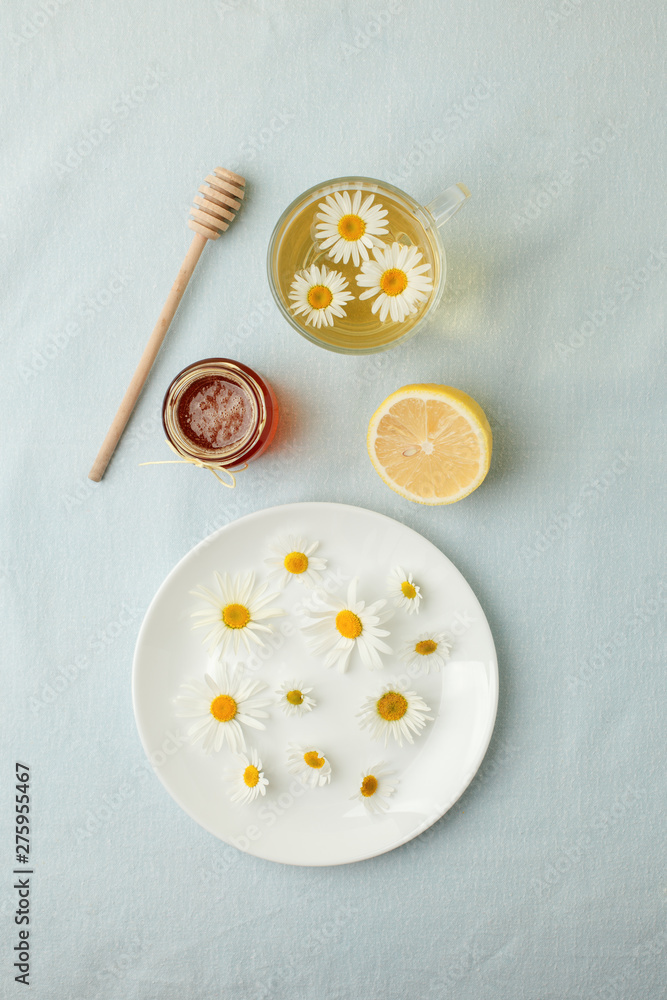 Chamomile flowers and chamomile tea. Chamomile tea in glass teacup with flowers, honey and lemon, top view, prevention of seasona flu colds Chamomile flowers and chamomile tea. Chamomile tea in glass teacup with flowers, honey and lemon, top view, prevention of seasona flu colds