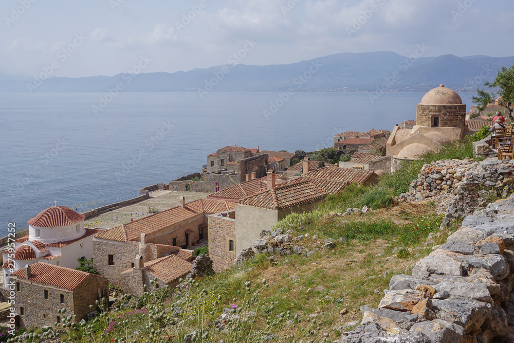 Monemvasia, Greece: Two tourists in a cafe above St. Nicholas Church (right) and the Church of Christ in Chains (left), overlooking the Aegean Sea.