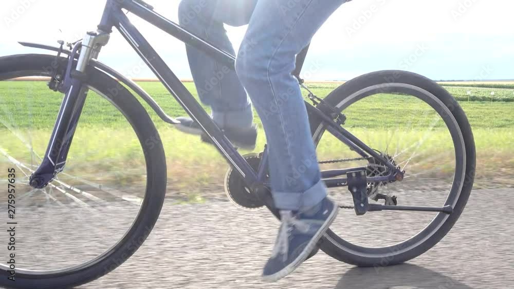 Close Up Bicycle Wheel and Pedals Gear System Road Bike. Cyclist Riding on Road at Sunset. Close Up Bicycle Wheel and Pedals Gear System Road Bike. Cyclist Riding on Road at Sunset.