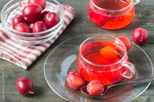 Konstfotografi Two transparent glass cups with cooked compote of plums on an old wooden table