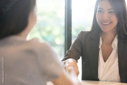 Portrait young Asian woman interviewer and interviewee shaking hands for a job interview .Business people handshake in modern office. Greeting deal concept photo