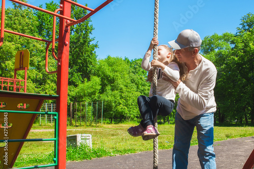 Father helps his child's daughter to climb the rope. Concept of helping young people
