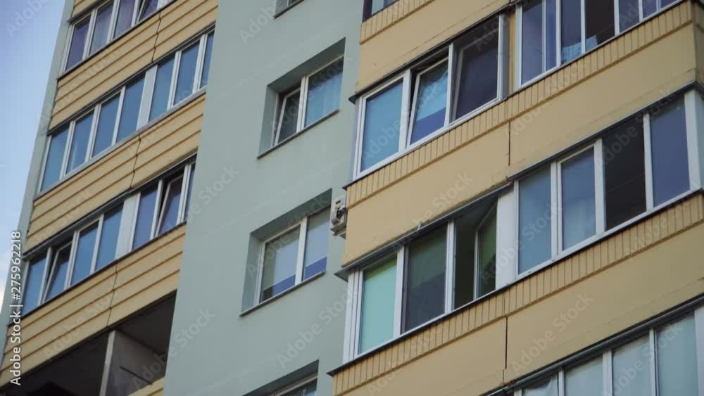 Close up shot of soviet union residential building. Residential building exterior with blue sky background. green house facade. The building features exterior green wall and small balconies Close up shot of soviet union residential building. Residential building exterior with blue sky background. green house facade. The building features exterior green wall and small balconies