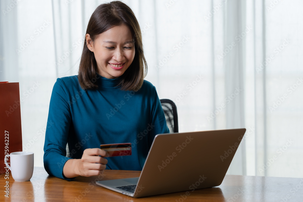 Happy Asian woman shopping online and paying by credit card.technology and ecommerce concept Happy Asian woman shopping online and paying by credit card.technology and ecommerce concept