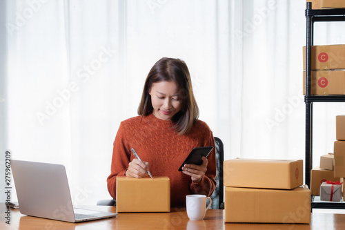 Beautiful Asian girl shop online are writing the customer's address down to the delivery box.