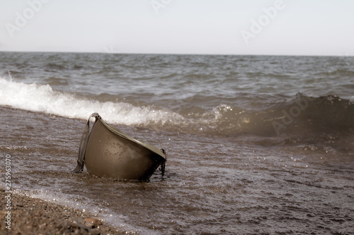 Vászonkép vintage photo of military helmet on beach in the water.